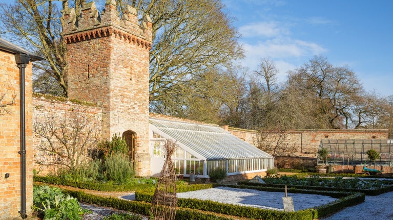 An image showing frost on the ground in he kitchen garden and the vegetable beds emptied out ready for spring.